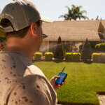 Man using remote to start sprinkler system in front lawn