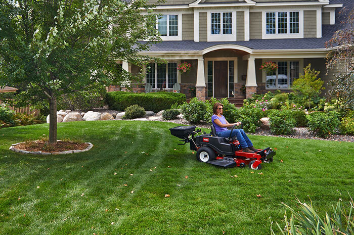 Woman using Toro Timecutter Z Seed Spreader in front yard