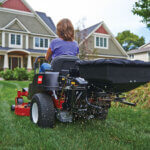 close up of seeder attachment on back of Toro TimeCutter zero turn mower spreads seed in residential yard