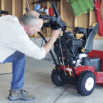 Man in garage assembling a Toro Two Stage Snowblower