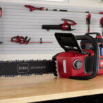 an electric chainsaw sits on a workbench, many other electric tools shown in the background