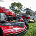 close up shot of Toro gas walk mower with electric Toro walk mower in the background