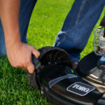 Man adjusts height of cut on walk mower