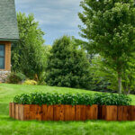 Container garden full of vegetable plants sits in a yard