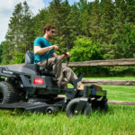 man mows open pasture along a fence with Toro zero turn